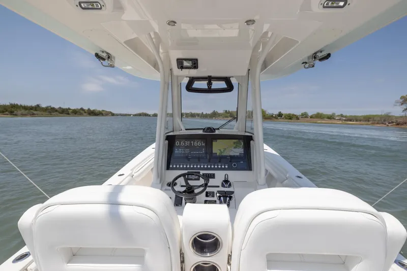Slide: The Image of 2021 Regulator 28FS boat interior with seating, on a sunny day near a bridge. - 11