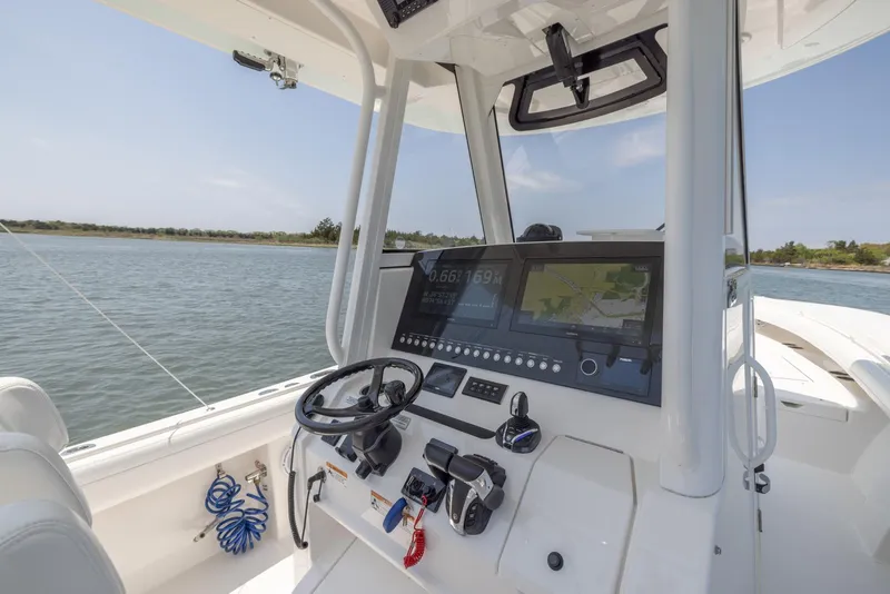 Slide: The Image of 2021 Regulator 28FS boat interior with steering console on calm water. - 12