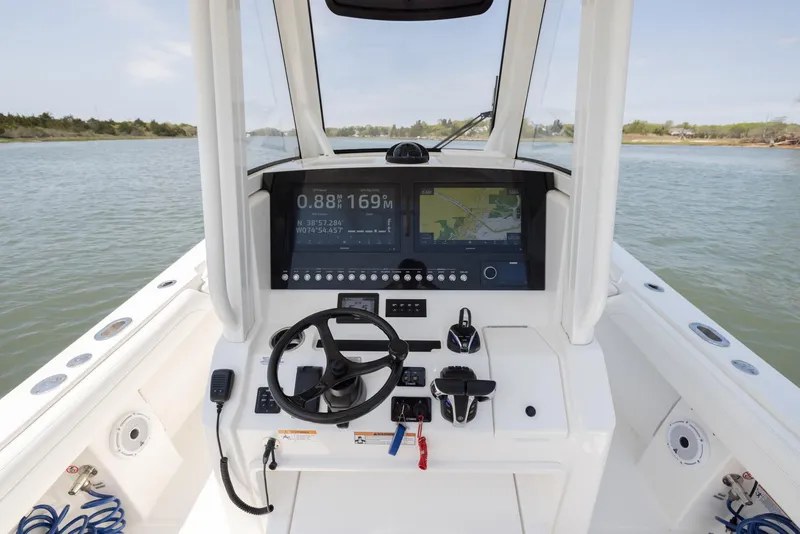 Slide: The Image of 2021 Regulator 28FS boat cockpit with steering wheel and navigation system on open water. - 13