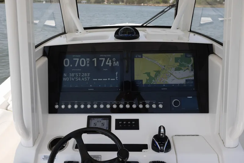 Slide: The Image of 2021 Regulator 28FS boat console with steering wheel and navigation screens on calm water. - 14