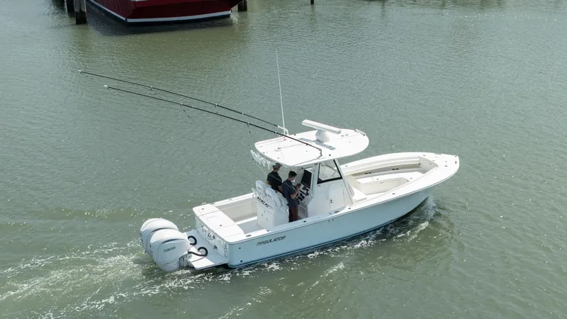 Slide: The Image of 2021 Regulator 28FS boat on calm water near a bridge and shoreline. - 2