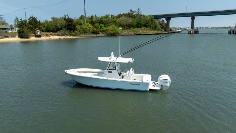 Slide: The Image of 2021 Regulator 28FS boat on calm water, featuring fishing rods and a sleek design. - 5