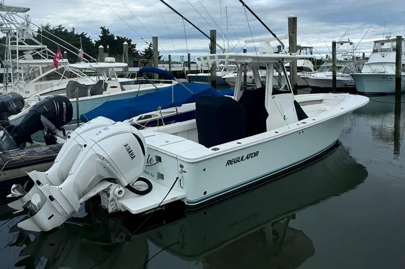 Slide: The Image of 2021 Regulator 28FS boat on calm water, featuring dual outboard engines. - 6