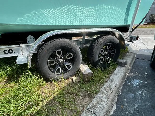 Slide: The Image of Trailer wheels of 2025 May-Craft 2000 Cape Classic boat on grass and pavement. - 5