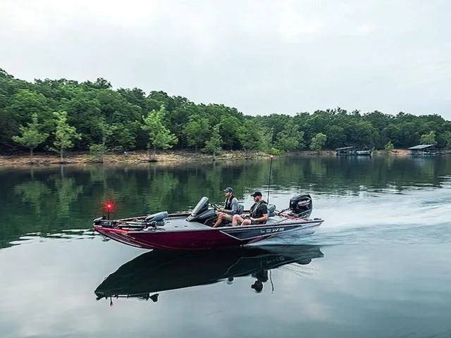 Slide: The Image of 2025 Lowe Stinger 175C boat cruising on a serene lake with lush green trees. - 1