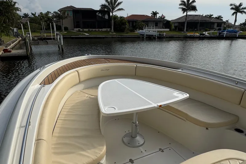Slide: The Image of 2015 Chris-Craft Catalina 29 boat with cushioned seating and table, docked by waterfront homes. - 18