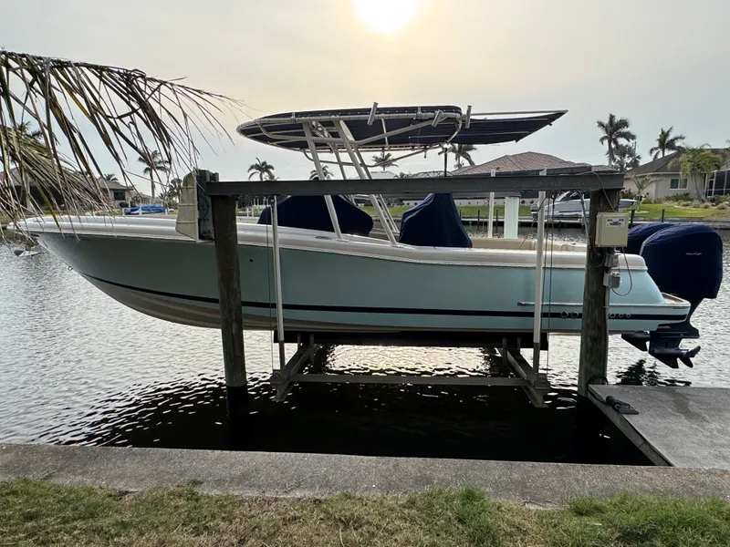 Slide: The Image of 2015 Chris-Craft Catalina 29 boat on lift by waterfront, palm trees in background. - 2