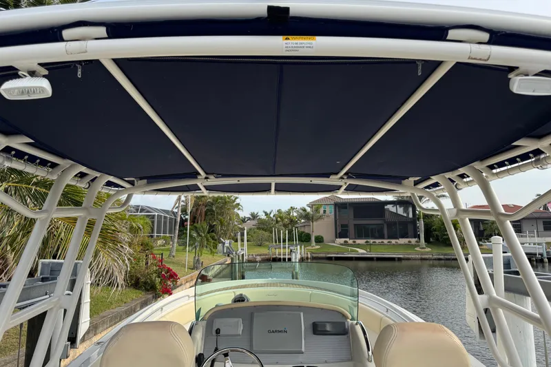 Slide: The Image of 2015 Chris-Craft Catalina 29 boat interior with canopy, docked near waterfront homes. - 23