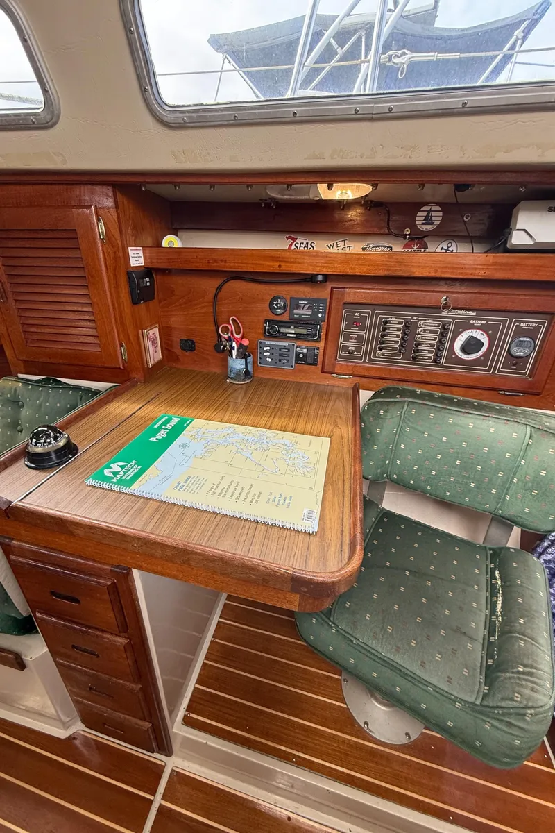 Slide: The Image of 1986 Catalina 36 yacht interior with navigation station, wooden desk, and green cushioned chair. - 11