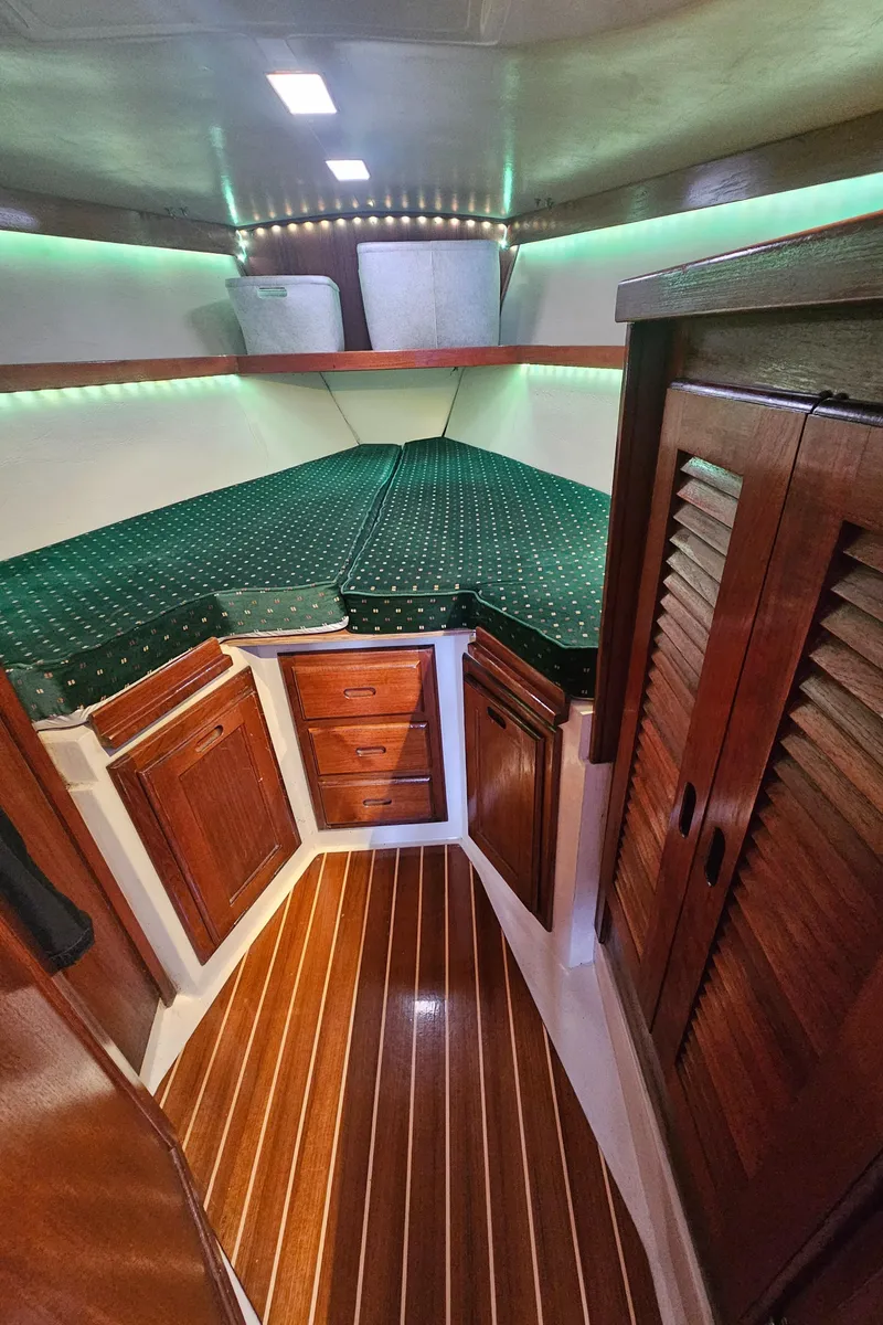 Slide: The Image of 1986 Catalina 36 yacht interior with wood cabinetry and green cushioned bed. - 18