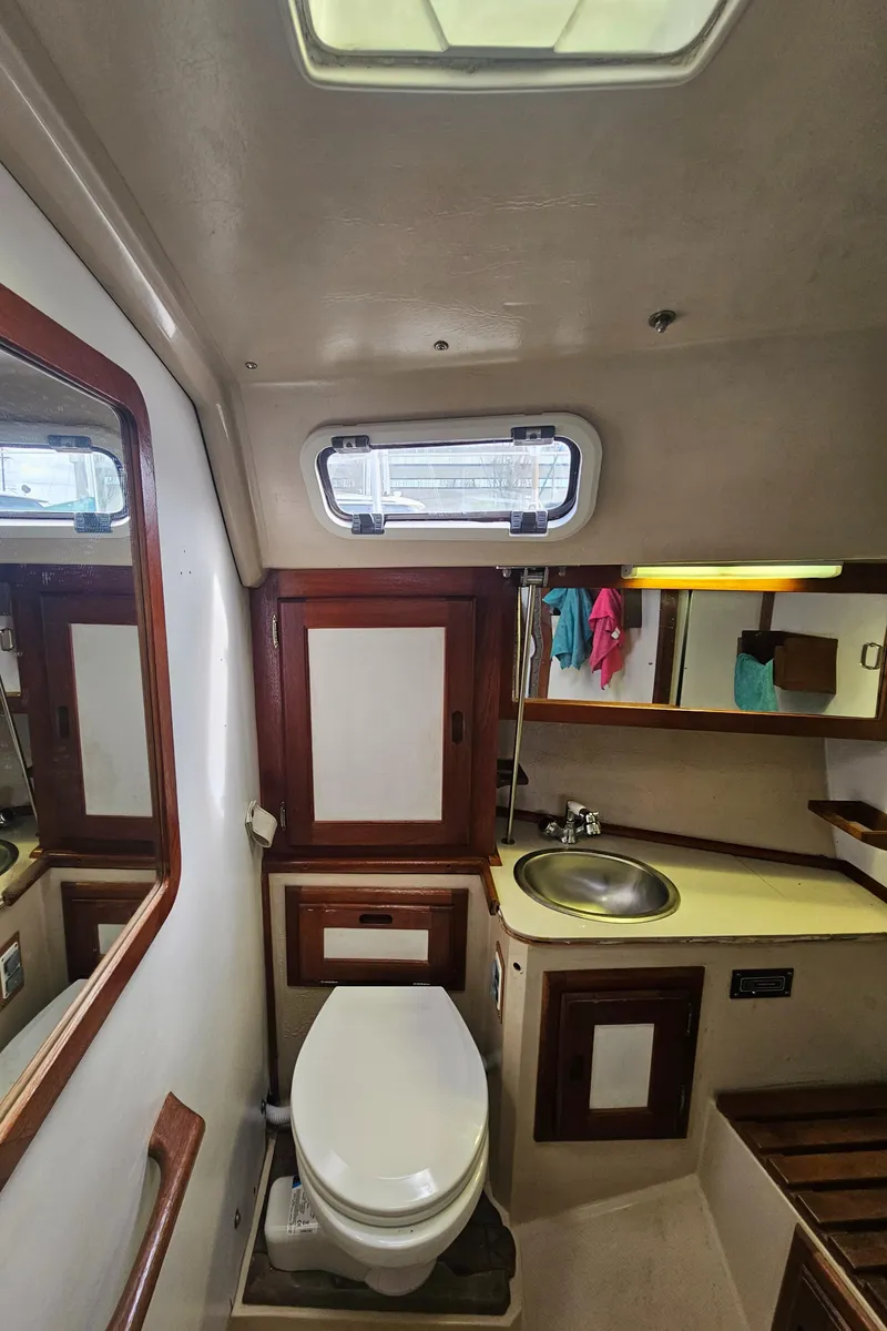 Slide: The Image of 1986 Catalina 36 yacht bathroom with sink, toilet, mirror, and porthole window. - 22