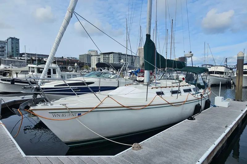 Slide: The Image of 1986 Catalina 36 sailboat docked in a marina, surrounded by other boats and cityscape. - 4