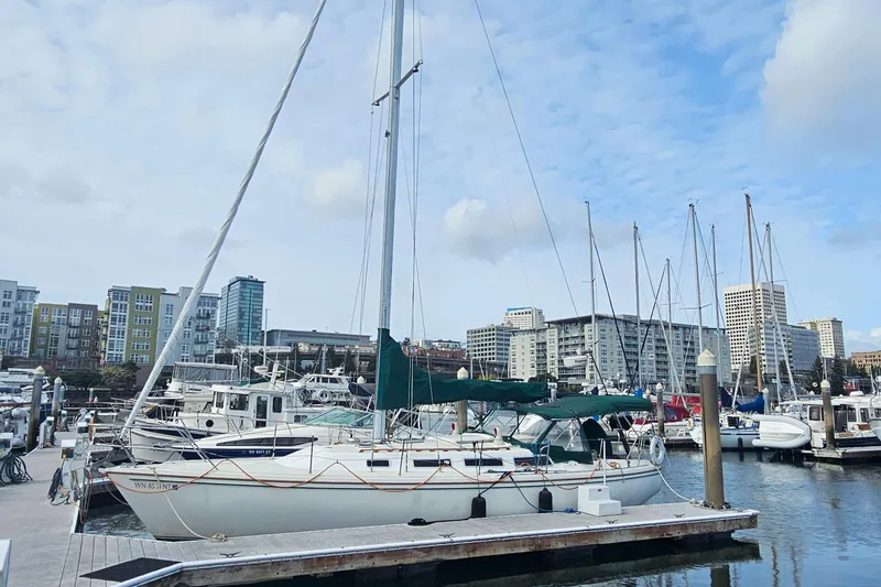 Slide: The Image of 1986 Catalina 36 sailboat docked in a marina with cityscape background. - 42