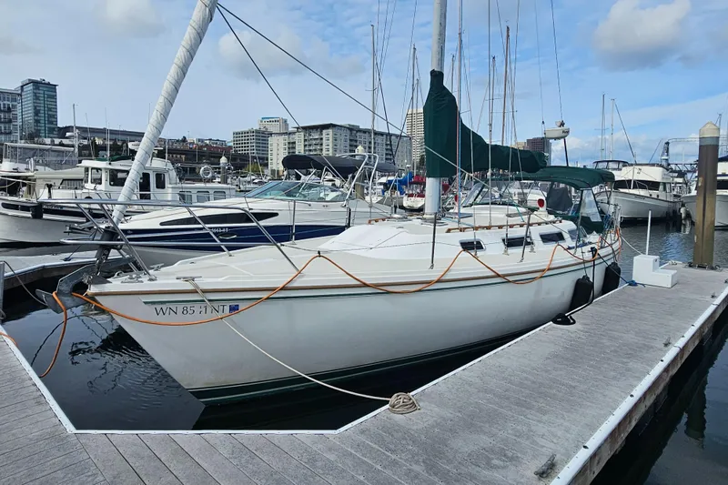 Slide: The Image of 1986 Catalina 36 sailboat docked at marina, surrounded by other boats and cityscape. - 43