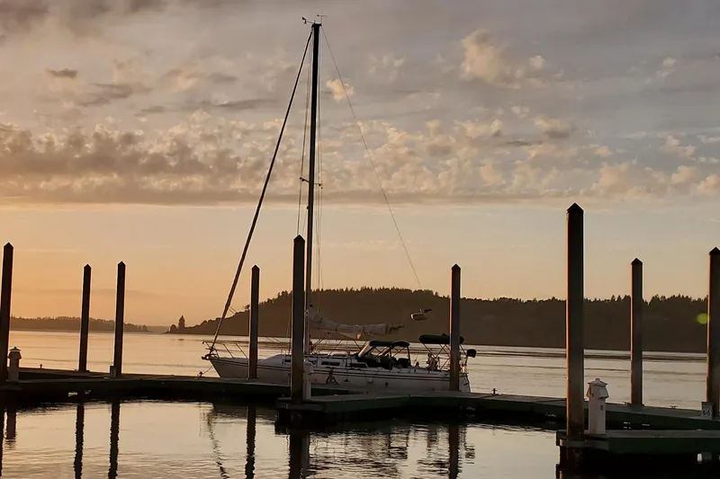 Slide: The Image of 1986 Catalina 36 sailboat docked at sunset with calm waters and scenic background. - 44