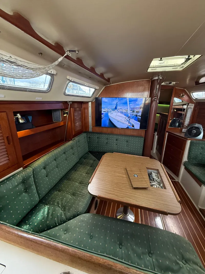 Slide: The Image of Interior of 1986 Catalina 36 sailboat with green seating and wooden table. - 5