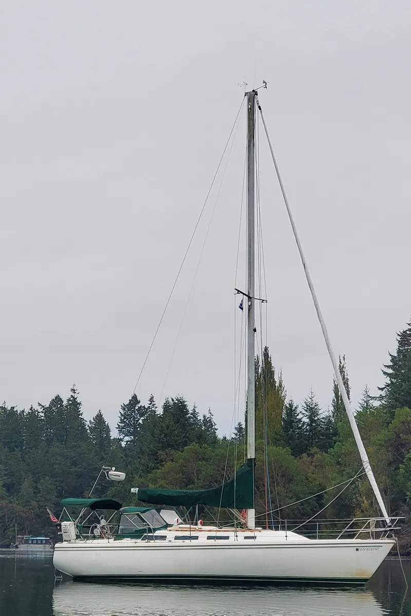 Slide: The Image of 1986 Catalina 36 sailboat on calm water, surrounded by trees. - 52