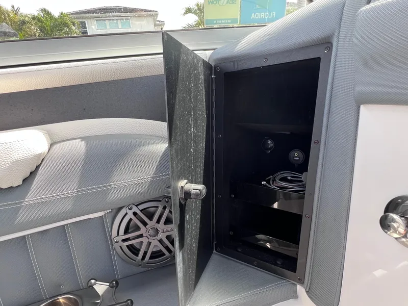 Slide: The Image of 2019 Cobalt 25 SC boat interior with open storage compartment and speaker. - 33
