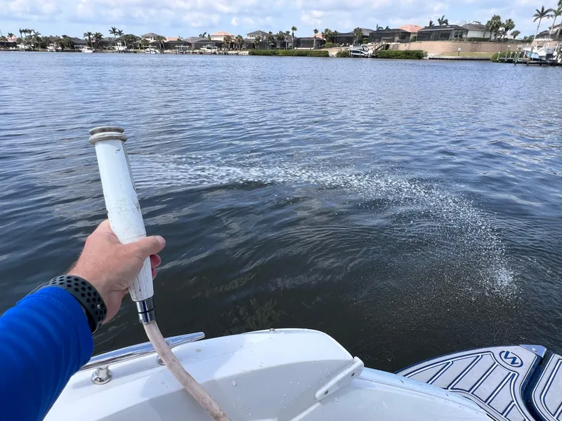 Slide: The Image of Man using hose on 2019 Cobalt 25 SC boat in freshwater setting. - 38