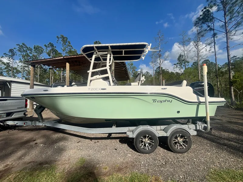Slide: The Image of 2022 Bayliner Trophy T20CX boat on trailer, parked outdoors under clear sky. - 0