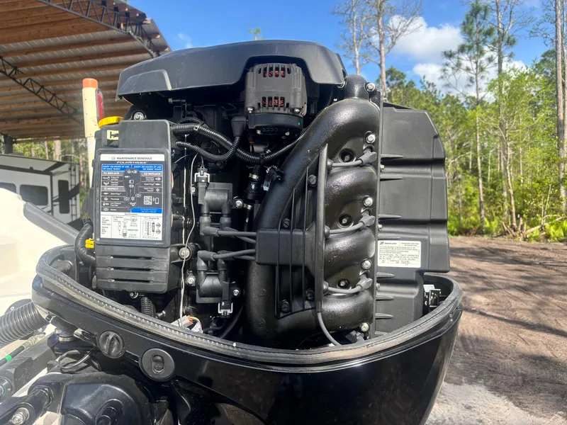 Slide: The Image of 2022 Bayliner Trophy T20CX outboard engine, detailed view, outdoors with trees in background. - 16