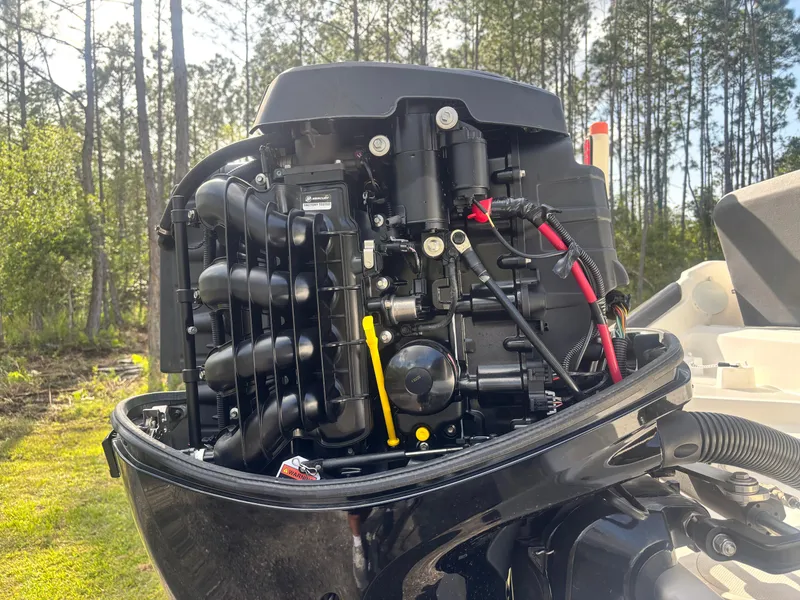 Slide: The Image of 2022 Bayliner Trophy T20CX outboard motor with open cover, set against a forest backdrop. - 18