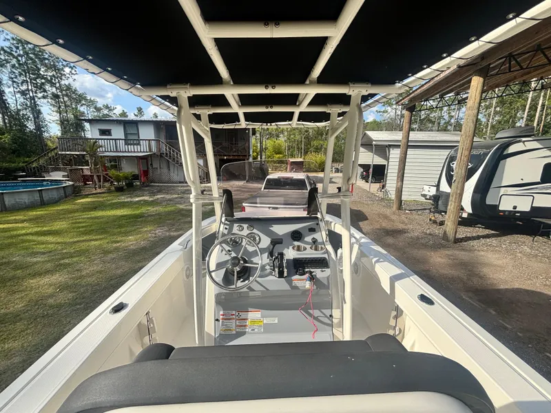 Slide: The Image of 2022 Bayliner Trophy T20CX boat interior with steering wheel and seating, parked outdoors. - 19