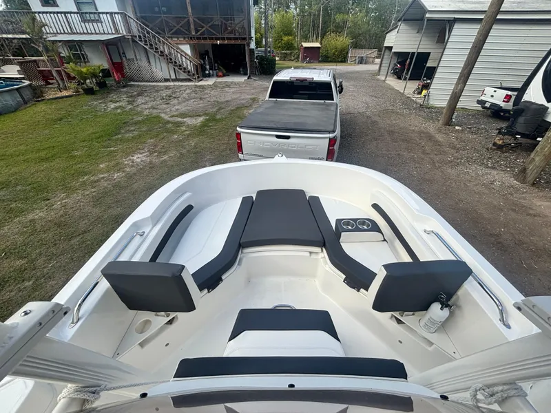 Slide: The Image of 2022 Bayliner Trophy T20CX boat interior with seating, parked near a pickup truck. - 25