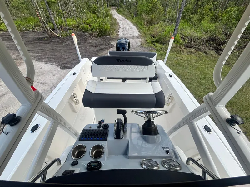 Slide: The Image of 2022 Bayliner Trophy T20CX boat interior with steering console and seating, surrounded by lush greenery. - 36