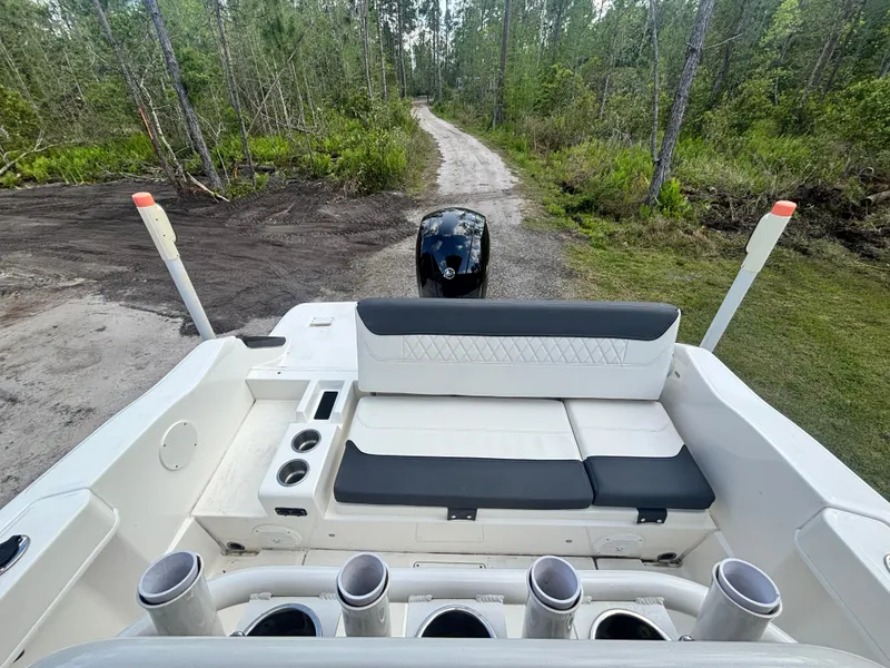 Slide: The Image of 2022 Bayliner Trophy T20CX boat interior with seating and rod holders, surrounded by forest path. - 37