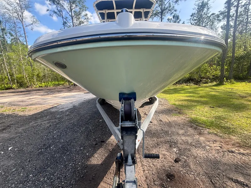 Slide: The Image of 2022 Bayliner Trophy T20CX boat on trailer, parked outdoors with trees in background. - 5