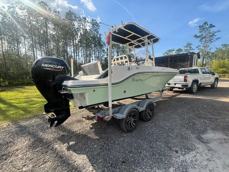 Slide: The Image of 2022 Bayliner Trophy T20CX boat on trailer, parked outdoors with a truck nearby. - 9