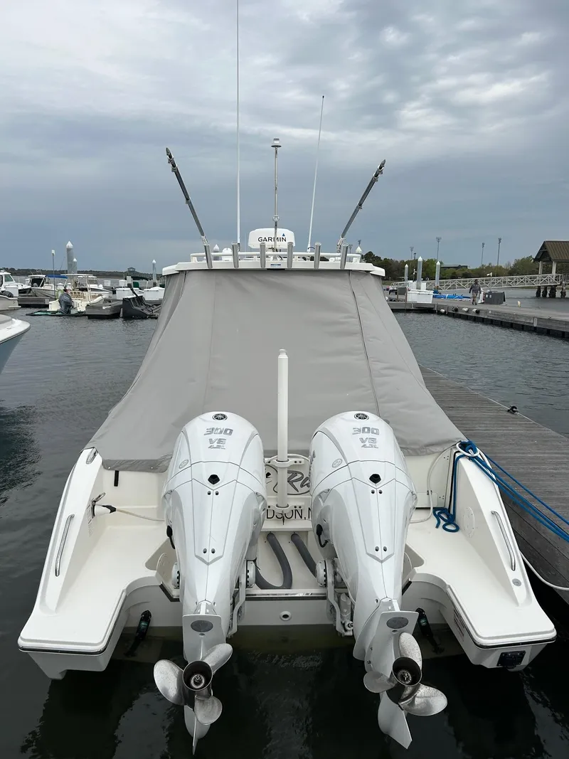 Slide: The Image of 2021 Pursuit S 328 Sport boat with twin outboard engines docked at a marina. - 13