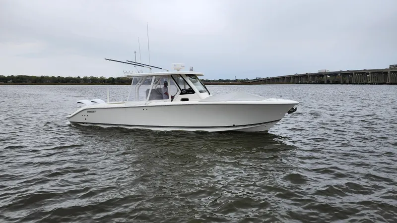 Slide: The Image of 2021 Pursuit S 328 Sport boat on calm water near a bridge. - 2
