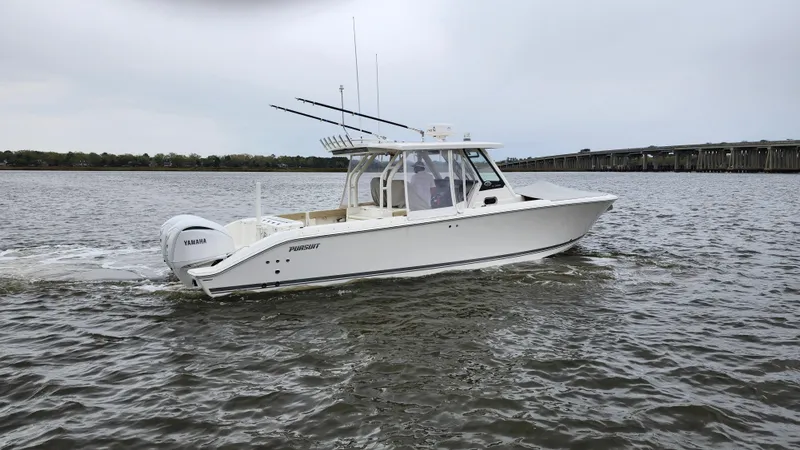Slide: The Image of 2021 Pursuit S 328 Sport boat cruising on a calm river near a bridge. - 4