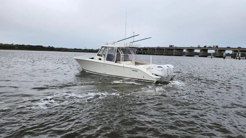 Slide: The Image of 2021 Pursuit S 328 Sport boat cruising on open water near a bridge. - 7
