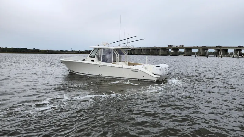 Slide: The Image of 2021 Pursuit S 328 Sport boat cruising on a calm river near a bridge. - 8