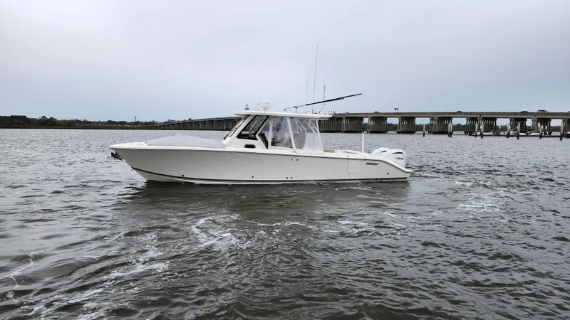 Slide: The Image of 2021 Pursuit S 328 Sport boat cruising on a calm river near a bridge. - 9