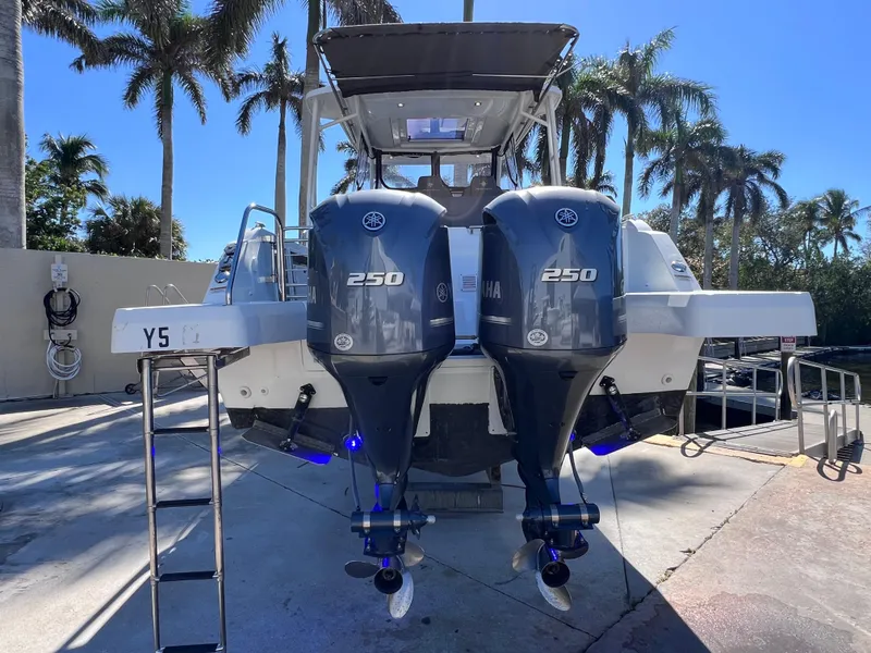 Slide: The Image of 2021 Jeanneau Leader 9.0 WA with twin Yamaha 250 engines, docked under palm trees. - 6