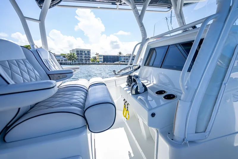 Slide: The Image of 2019 Yellowfin 34 boat interior with luxurious seating and steering console, docked by waterfront. - 17