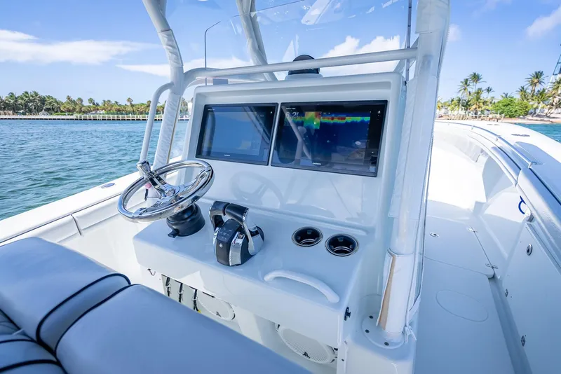 Slide: The Image of 2019 Yellowfin 34 boat helm with dual screens, steering wheel, and controls on open water. - 20