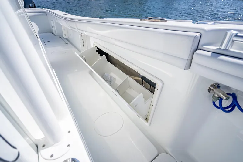 Slide: The Image of 2019 Yellowfin 34 boat interior with open storage compartment, white finish, and ocean backdrop. - 43