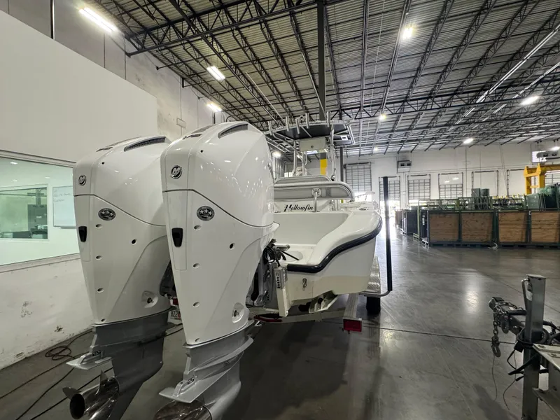 Slide: The Image of 2019 Yellowfin 26 Hybrid boat with dual engines in a spacious warehouse. - 2