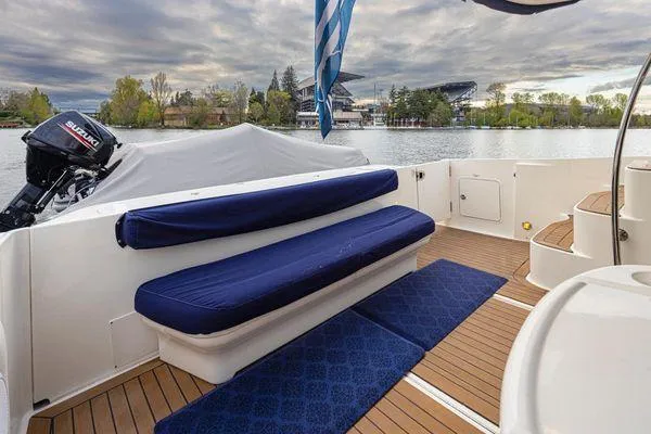 Slide: The Image of 2005 Sea Ray 520 Sedan Bridge yacht with blue seating, wooden deck, and scenic waterfront view. - 13
