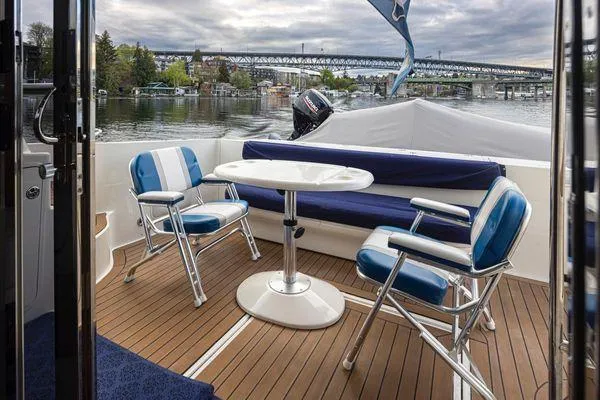 Slide: The Image of 2005 Sea Ray 520 Sedan Bridge yacht deck with seating and table, overlooking a scenic waterfront. - 17