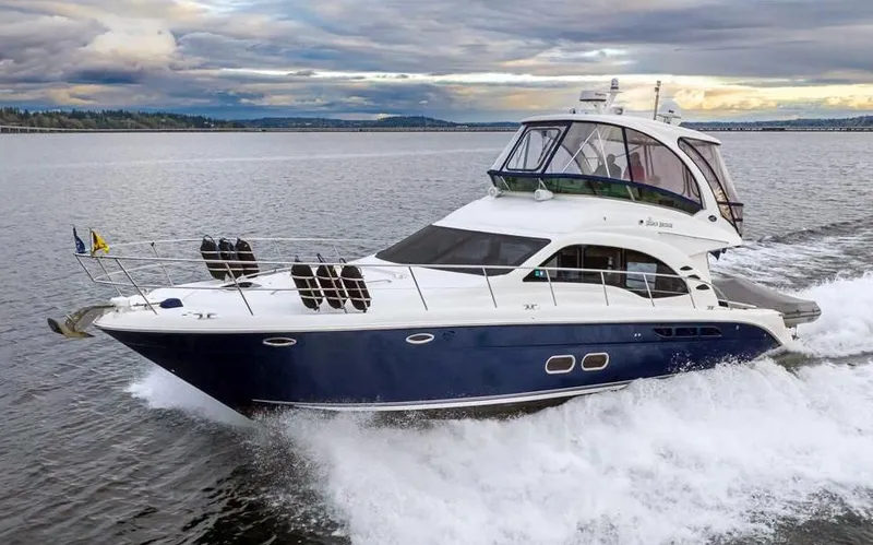 Slide: The Image of 2005 Sea Ray 520 Sedan Bridge yacht cruising on open water under cloudy skies. - 2