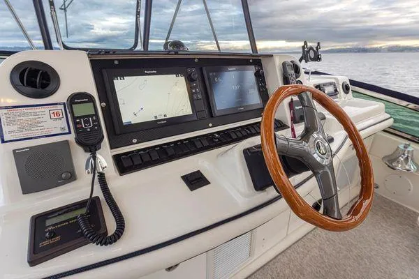 Slide: The Image of 2005 Sea Ray 520 Sedan Bridge helm with navigation screens and wooden steering wheel. - 25