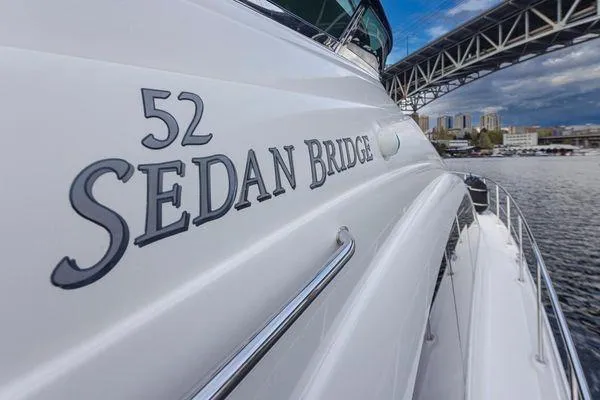 Slide: The Image of 2005 Sea Ray 520 Sedan Bridge yacht near a bridge, city skyline in background. - 8