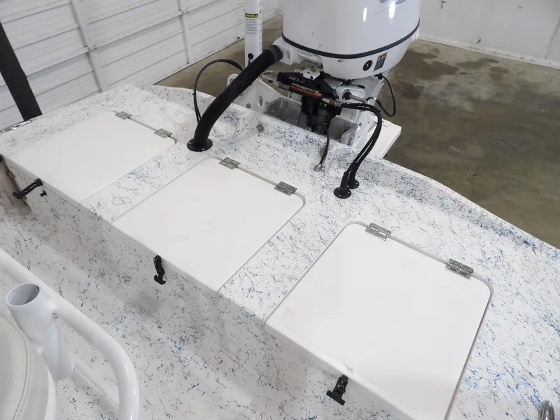 Slide: The Image of 2022 Freedom 18 PATRIOT boat deck with storage hatches and motor in a garage setting. - 17