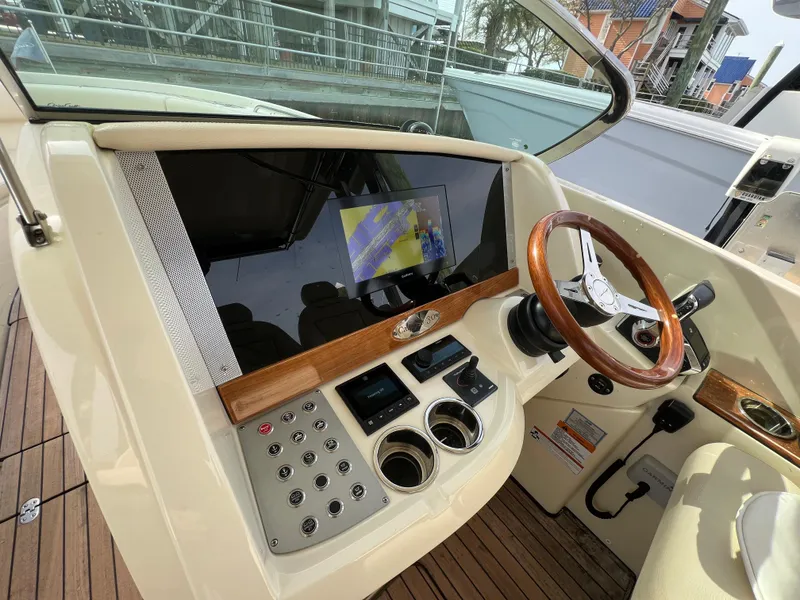 Slide: The Image of 2022 Chris-Craft Calypso 30 helm with wooden steering wheel and modern controls. - 17